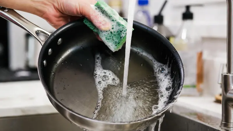 Lavando una sartén de acero al carbono nueva con agua caliente y jabón para quitar la cera de fábrica.