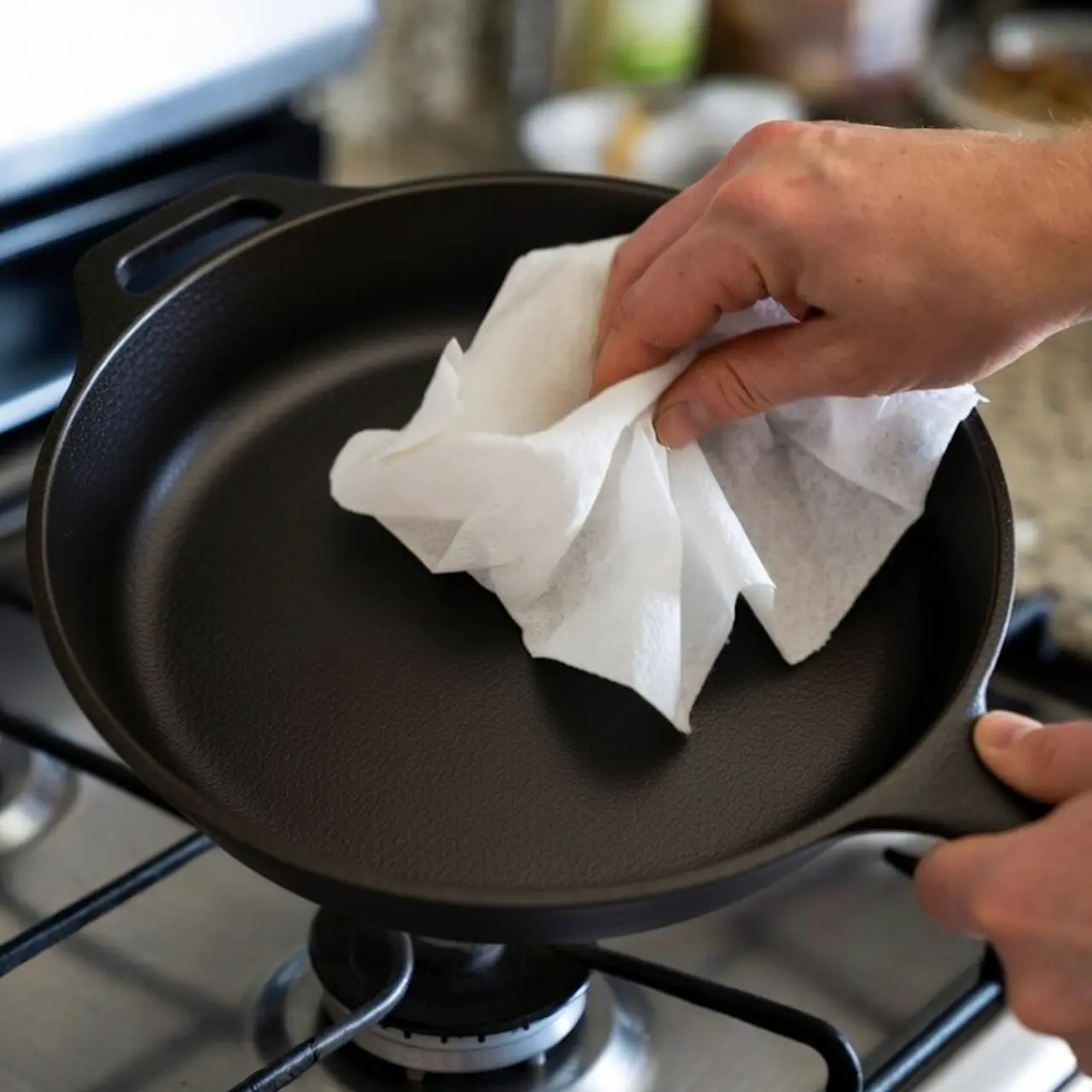 Sartén de hierro fundido secándose sobre un quemador de estufa encendido a fuego medio, con un ligero vapor visible.