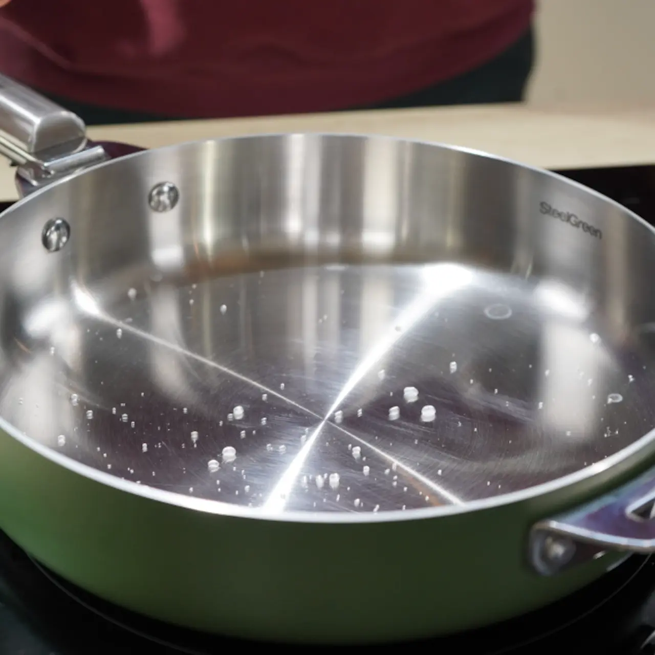 Una gota de agua rodando intacta sobre la superficie de acero inoxidable caliente.