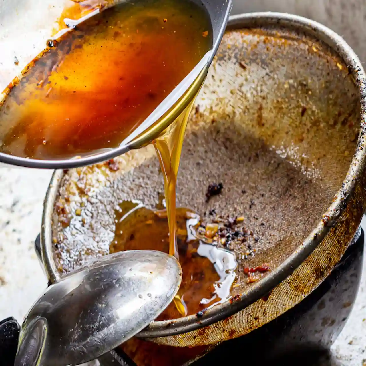 Aceite de freír oscuro y espumoso mostrando signos de degradación química.