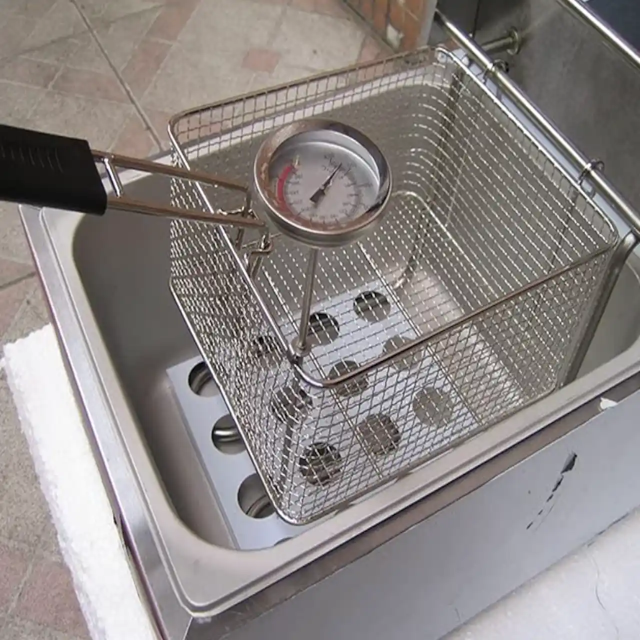 Termómetro de cocina midiendo el calor en la superficie de una sartén sobre inducción.