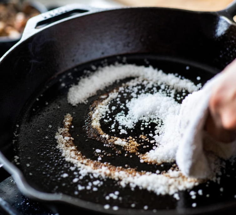 Sartén de hierro fundido siendo limpiada con el método tradicional